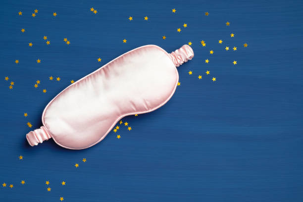 Pink blindfold on classic blue background with confetti. Sleep mask for eyes, relaxation and protection. Flat lay, top view