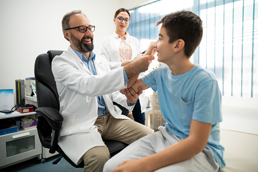 The doctor examines the mobility of his young patient's arm and discusses the diagnosis with his colleague.