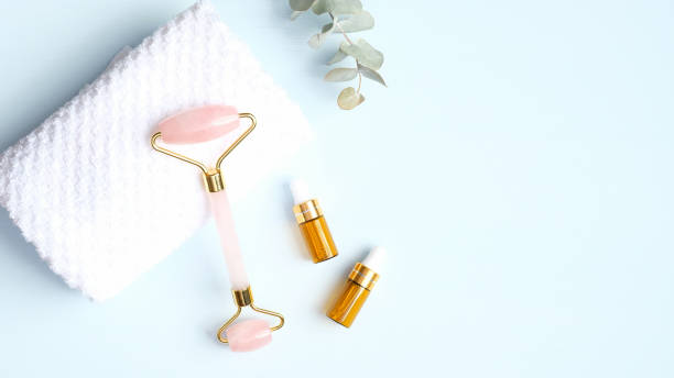 istock Jade roller for face and essential oil with towel on blue background. Flat lay, top view, copy space. Rose quartz facial massage tool, beauty tool for skin care concept 1218383292