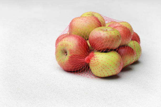 istock Small apples in a plastic mesh sack on a white background 1218384994