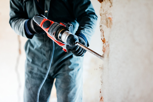trabajador utilizando taladro de martillo neumático para cortar el ladrillo de hormigón de pared, photo