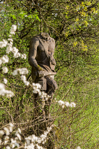 Schaffhausen, Switzerland - April 09. 2020: A headless old soldier statue with a sword in hand stands in oblivion in forest at the foot of the medieval castle Herblingen, Switzerland. It is a Swiss heritage site of national significance.