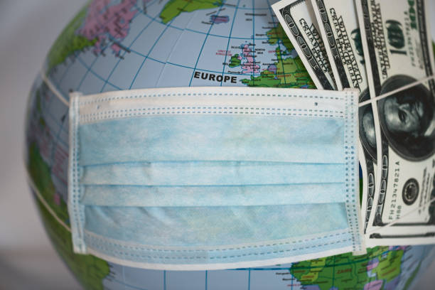 istock Globe with money covered with respiratory mask - Covid 19 1218389720
