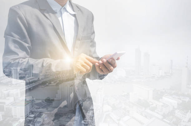 istock double exposure business man hands use smartphone typing on screen for working with technology wireless communication connection with cityscape building background. 1218396388