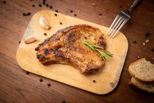 Grilled pork chop with spices and bred on wooden background