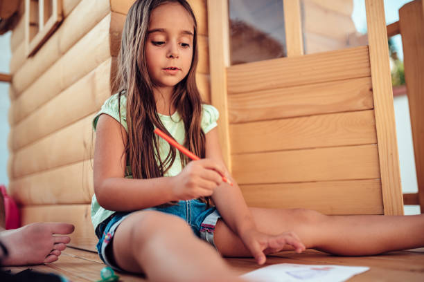 istock Girl playing in treehouse and drawing with colored pencils 1218398489