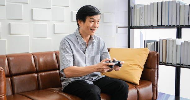istock Senior Asian man using tablet and virtual reality simulator playing games in living room and feeling happy . Lifestyle Senior family at home concept. 1218402667