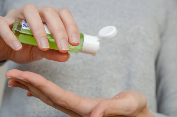 istock Women's hands using green antibacterial hand gel close up 1218405060