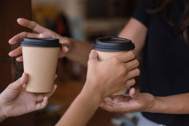 Sharing is caring Close up shot of female volunteer giving out takeaway coffee for neighbor , during Covid 19 quarantine paper coffee cup stock pictures, royalty-free photos & images