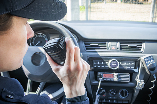 Micrófono de una radio o walkie-talkie en la mano de una mujer oficial de policía en su coche de policía patrulla. photo