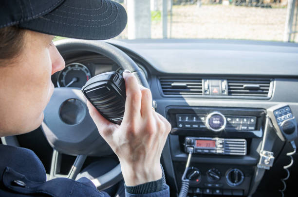 microfono di una radio o walkie-talkie in mano a un agente di polizia donna nella sua auto della polizia di pattuglia. - talkie foto e immagini stock