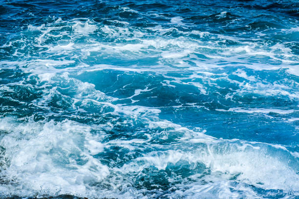 istock Waves crashing on rocks in blue ocean. 1218407307