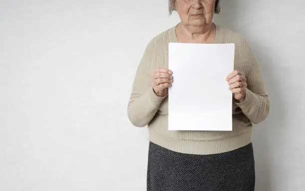 Old senior woman with empty white blank in her hands for copy space