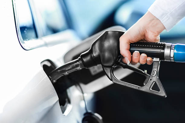 Woman pumping petrol at gas station into vehicle. stock photo