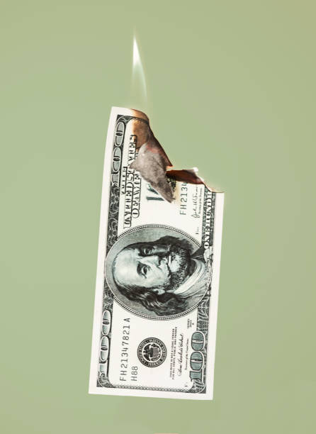 istock Burning hundred dollars cash on green background 1218419332