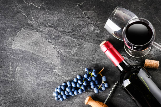 istock Fresh bunch grapes and bottle of red wine on dark stone table with copy space. 1218421207