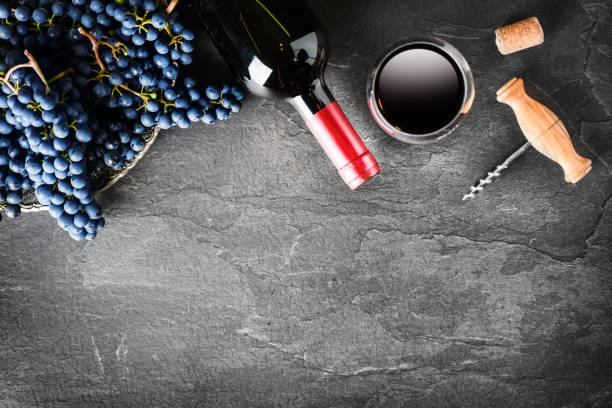 istock Fresh bunch grapes and bottle of red wine on dark stone table with copy space. 1218421219