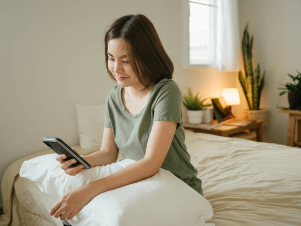 istock Millennial girl using her phone on the bed 1218422241