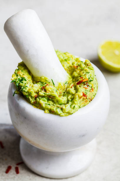 istock Cooking guacamole - avocado sauce in a white stone mortar. 1218422657