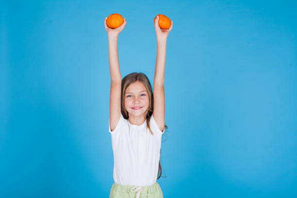istock beautiful girl raised her hands with two oranges 1218424162