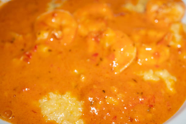 shrimp and grits with a tomato cream sauce topped with basil - grits prepared shrimp restaurant food imagens e fotografias de stock