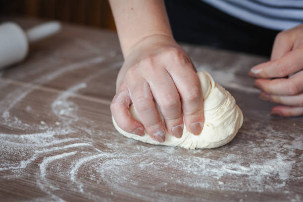 istock Female hands kneading a dough on a wooden table 1218426720