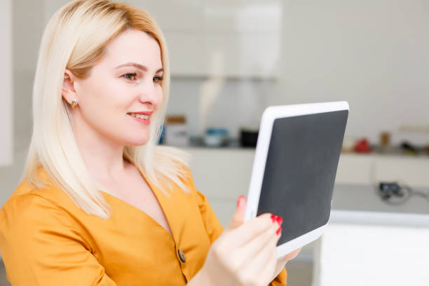 istock mid adult woman sitting on sofa with tablet pc. Horizontal shape, front view, copy space 1218435351