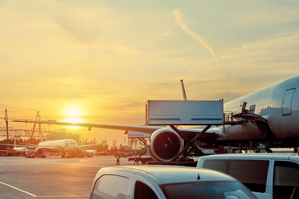 modern passenger airplane parked to terminal building gate at airside apron of airport with close up airplane parts jet engine wing windows gear tow tractor noon sun view - jet way imagens e fotografias de stock