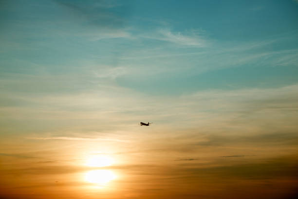 Commercial airplane flying above clouds in dramatic sunset light.