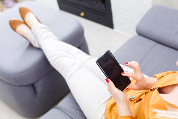 istock Woman at home relaxing on sofa couch reading email on the tablet computer wifi connection 1218437478