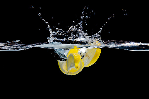 A studio shot of a group of lemon wedges splashing into water.