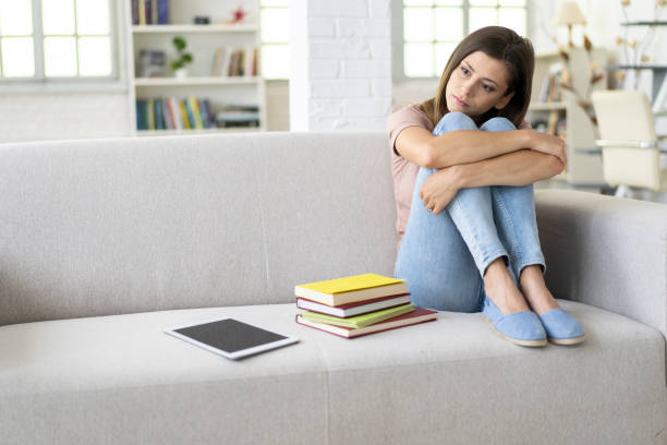 istock Sad woman sitting at home 1218439741