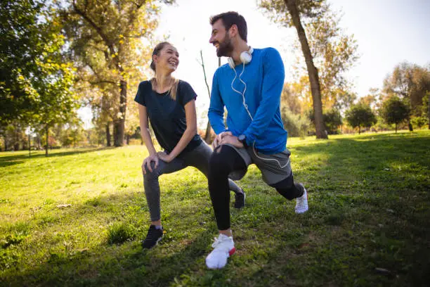 Cheerful athletic couple exercising outdoors in a public park, living a healthy lifestyle.