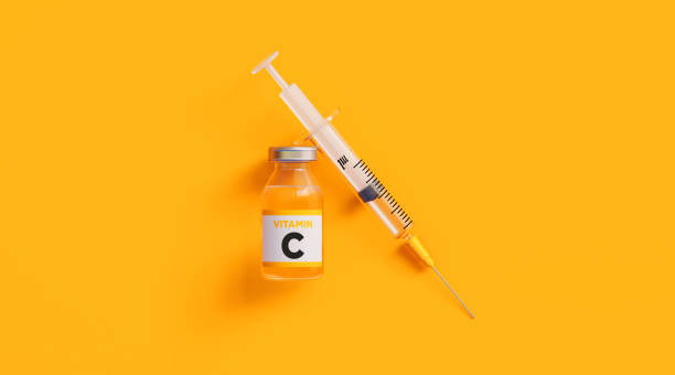istock Injectable C Vitamin  and Syringe on Yellow Background 1218443591