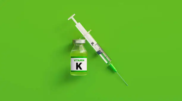 Injectable vitamin K and syringe on green background, Horizontal composition with copy space. Vitamin K concept.