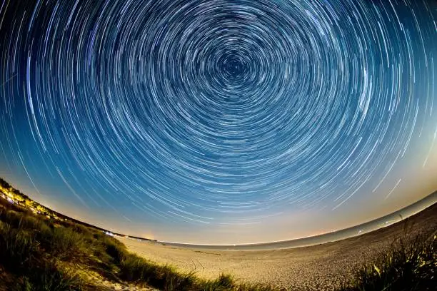 star trails at the beach of the baltic sea in summer with polaris