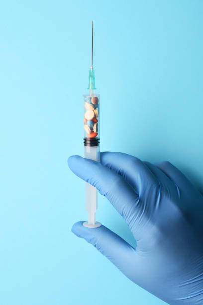 istock Multi colored pills in the syringe, doctor hand holding syringe 1218444768