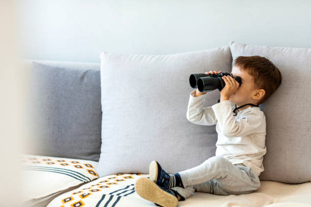 istock Boy looking through binoculars from the living room 1218444864