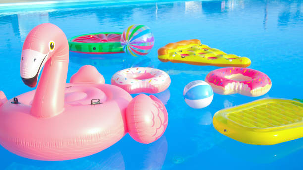 close up: les jouets gonflables à la mode flottent autour de la piscine vide par une journée ensoleillée. - blue mattress vacations toy photos et images de collection