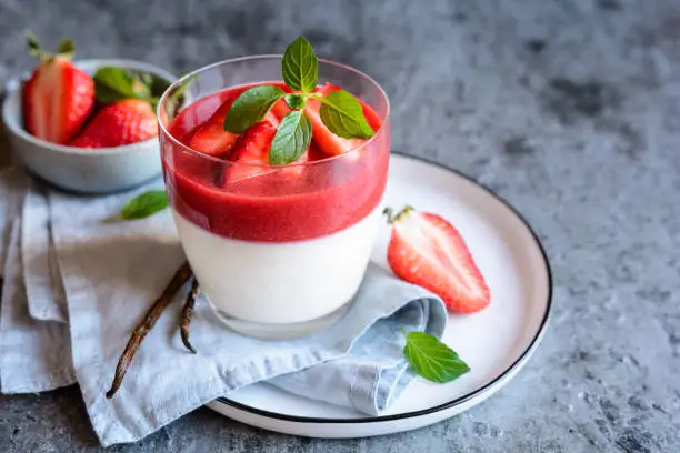 Photo of Panna cotta with strawberry sauce topping, served in a glass jar