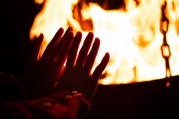 istock woman warming her hands by the campfire 1218449015