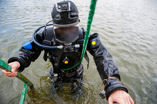 Diver in the water in a diving suit and helmet ready to dive