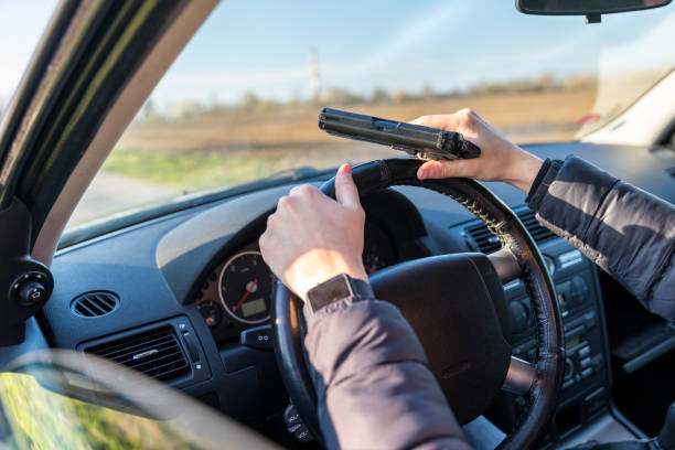 young man with gun in hand in passenger car on driver's seat young man with gun in hand in passenger car on driver's seat. gunman stock pictures, royalty-free photos & images