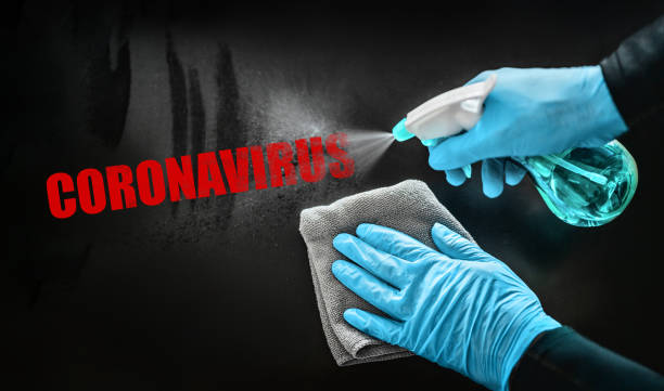 istock Coronavirus disinfecting surfaces cleaning home cleaning spraying aways red text with sanitizing spray bottle against COVID-19 wearing blue gloves. Sanitize surface prevention 1218449975