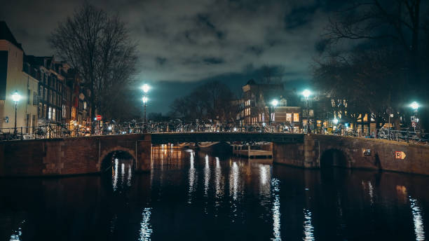 istock Canal with bridge in night illumination with clouds, Amsterdam, Netherlands 1218450336