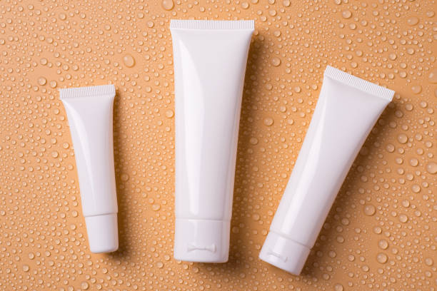 Top above overhead view photo of different size containers for blank empty cleanser toner tonic conditioner isolated over water drops beige background