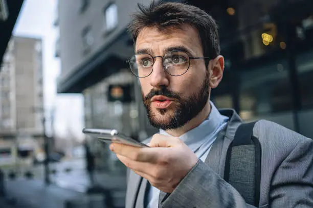 Photo of Young businessman on the move recording a voicemail on a mobile phone