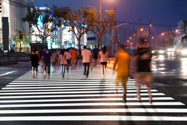 People in blurred motion crossing busy Asian street at night