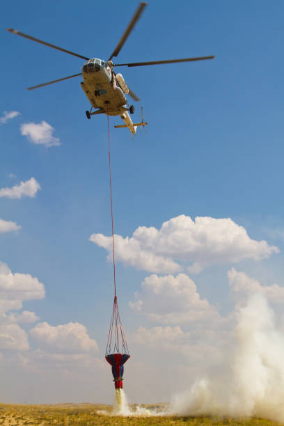 istock Firefighting helicopter with fire bucket flies 1218452997