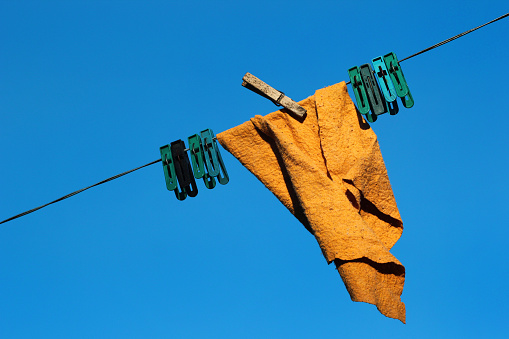 Duster with pegs on a clothesline against blue sky background